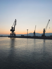 Fototapeta premium Silhouettes of the cranes in the sea port