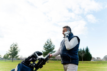 Senior using his smartphone while playing a game of golf