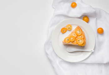 sweet cake dessert decorated with slices of kumquat tropical fruit on a white background with copy space. view from above