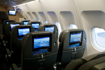 COPENHAGEN, DENMARK - NOV 24th, 2018: Empty airplane seats waiting for passengers and take off in an airplane. Empty plane interior before flight and departure. Watching movie on an aircraft