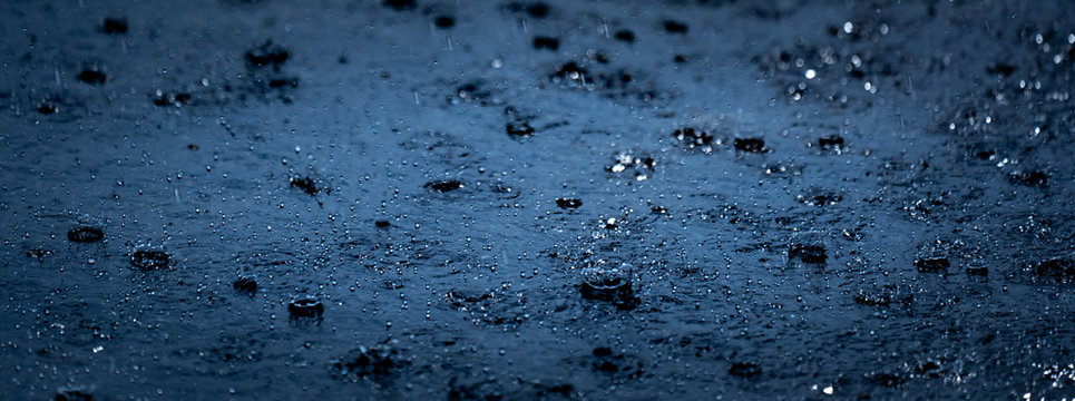 Rain falling on ground, dark black raining weather background, buble and splash on water surface, refresh nature on pattern of droplet water 