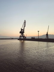 Obraz premium Silhouettes of the cranes in the sea port
