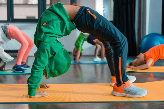Selective focus of children doing gymnastic bridge on fitness mats in sports center