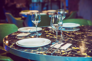 Top view copy space . Round marble table. Green chair. Set of cutlery knife, spoon, fork, plate, wine glass. Black marble table .