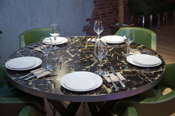Top view copy space . Round marble table. Green chair. Set of cutlery knife, spoon, fork, plate, wine glass. Black marble table .