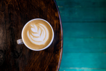 Cup of latte with art on table.