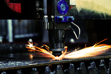 The laser machine cuts a metal sheet and bright sparks fly out of its work. Laser machine at a...
