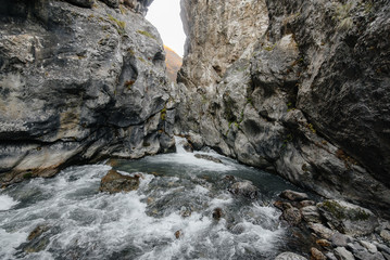 Fototapeta na wymiar A stormy mountain river flows through a gorge of mountains. Nature.