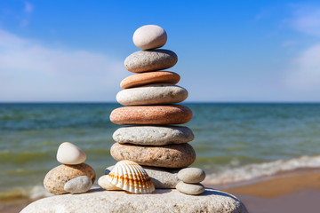 Rock zen pyramid of colorful pebbles on a beach on the background of the sea.