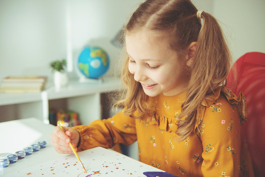 Pretty little girl paiting with colorful  crayon and paintbrush