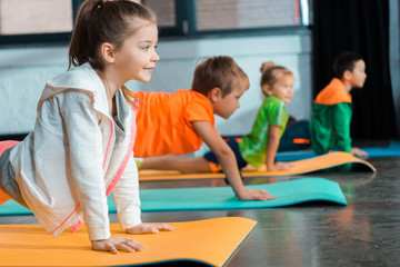 Selective focus of multicultural children doing asana on yoga mats