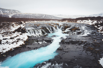 Bruarfoss waterfall in Icelandic scenery during sunset and cloudy sky. Turquoise
