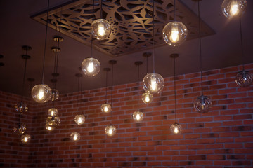 Beautiful retro luxury light lamp decor glowing. classic different retro light bulbs hanging on brick wall background at night . Decorative antique edison style light bulbs against brick .