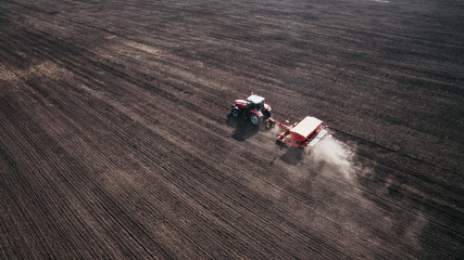 Aerial view of beautiful agriculture landscape and tractor on the field, harvesting the wheat from the soil.