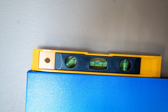 Titled uneven blue picture with a yellow hand tool