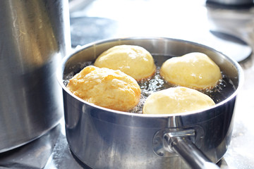 Donut, traditional sweets fried on Fat Thursday. Sweet cake, deep fried yeast dough donut. The cook is frying donuts.