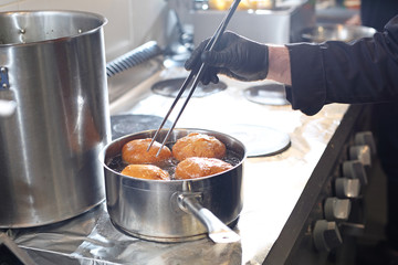 Fat Thursday, traditional sweet pastries. Sweet cake, deep fried yeast dough donut. The cook is frying donuts.