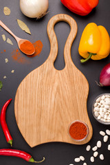 empty wooden board for text next to vegan ingredients vegetables and beans on a black background