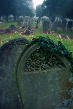 Dark mossy tombstones with blank copy space standing in misty graveyard
