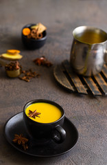 Obraz na płótnie Canvas Ayurvedic drink Golden milk made with ginger, turmeric, spices and milk in mag on concrete background. Alternative remedies for health