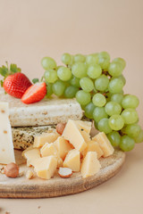 Two large pieces of salted pork lard and tasty cheese with hazelnut, strawberry and grape on old wooden board background. Rustic style. A delicious snack with bacon
