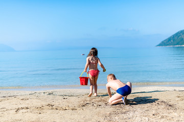 Two kids playing with the sand on the beach