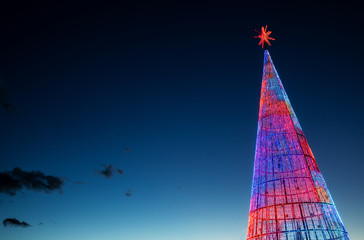 Artificial fir tree with colorful Christmas decorations LED strip light against the night sky