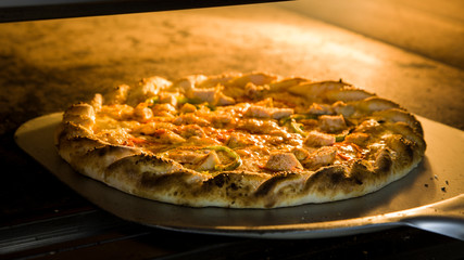 Delicious Pizza with a lot of ingredients baked in the oven,Italian Pizza,Putting pizza in oven at restaurant kitchen.