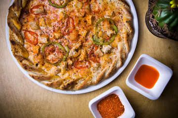 Food ingredients and spices for cooking mushrooms, tomatoes, cheese, onion, pepper, salt, and delicious italian pizza on black concrete background.