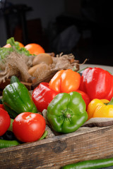 Tomatoes, color peppers and chilies in a wooden tray.