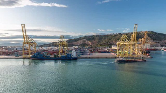 Aerial view of the sea cargo port and container terminal of Barcelona with the Montjuic hill timelapse, Barcelona, Catalonia, Spain. Ships loading by cranes. View from cruise terminal