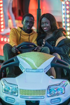 Black couple riding bumper car on funfair
