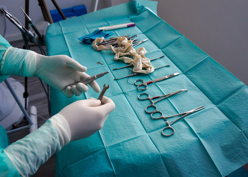 From above of faceless nurse in rubber gloves choosing tools for surgeon from table during operation in hospital 