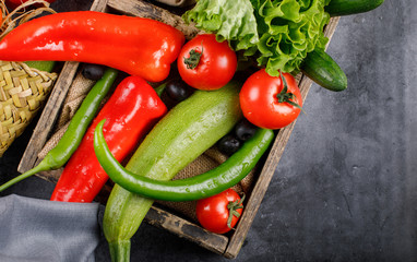 Chili peppers and tomatoes in a wooden tray.