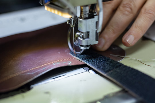 Shoemaker sewing a leather and velcro for making a shoe. Shoe sewing machine needle in focus. Sewing leather in focus. Shoe industry. 