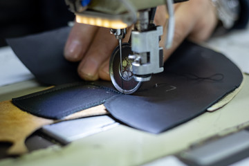 Fototapeta na wymiar Shoemaker sewing the black leather for making a shoe. Shoe sewing machine needle in focus. Sewing leather in focus. Shoe industry. 
