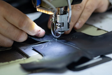 Fototapeta na wymiar Shoemaker sewing a leather for making a shoe. Shoe sewing machine needle in focus. Sewing leather in focus. Shoe industry. 