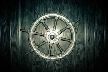 Old ship steering wheel on a wooden wall