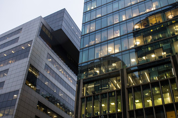 Fototapeta premium Fragment of the facade of a modern glass skyscraper with reflections and a lantern on the background of a cloudy sky with copy space