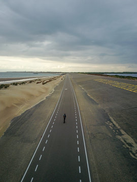 A man with long hair skating on a empty road in europe