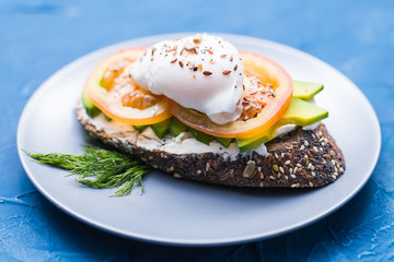 Sandwich with smoked salmon, egg and avocado on blue background. Concept for healthy nutrition.