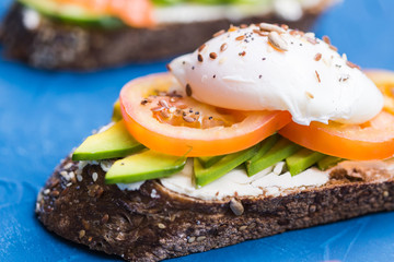 Sandwich with smoked salmon, egg and avocado on blue background. Concept for healthy nutrition.