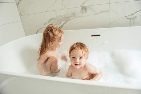 little brother and sister bathing in a foam bath