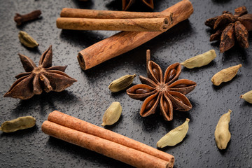 Cinnamon sticks, star anise and cumin seeds on a black background