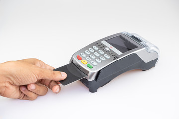 Close up man's hand using credit card swiping machine entering credit card code to pay shopping online on white table floor