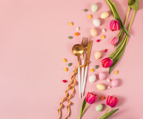 Easter festive dinner floral background with golden cutlery, tulips and eggs, easter and spring...