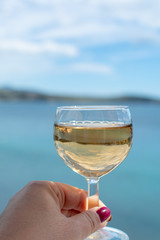 Woman hand with one glass of wine and blue sea view