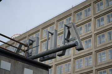 Backside of Big red letters of Alexanderplatz station sign with building in the back