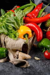Chili peppers mix with lettuce leaf in a wooden basket.