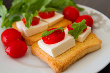 Fototapeta na wymiar Beautiful breakfast: toasts with goat cheese, tomatoes and Basil on a white plate
